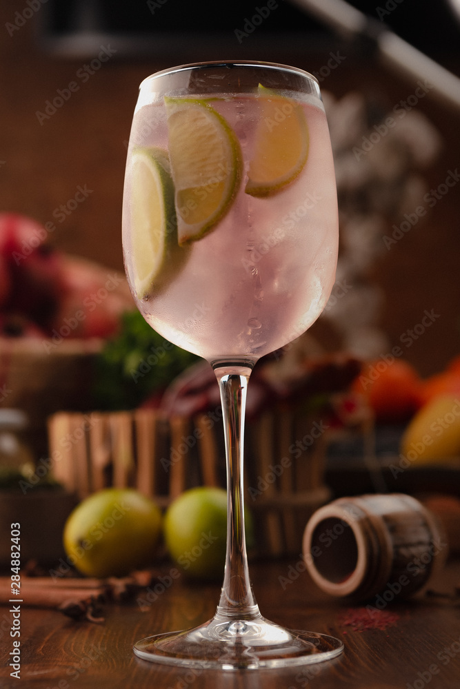 Wall mural cocktail dekorated lime in a vine glass on a wooden background. background decorated with fruits and