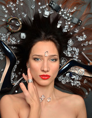 Portrait of a luxurious brunette girl lies in a placer of diamonds jewelry, luxury accessories