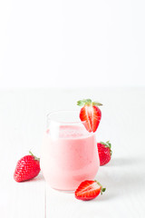 A glass of fresh strawberry smoothie on a wooden background. Summer drink shake, milkshake, juice and refreshment organic concept.