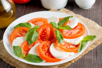 Close-up photo of caprese salad with ripe tomatoes, basil, buffalo mozzarella cheese. Italian and Mediterranean food concept. Fresh and healthy organic meal. Starter and antipasti.