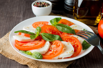 Close-up photo of caprese salad with ripe tomatoes, basil, buffalo mozzarella cheese. Italian and Mediterranean food concept. Fresh and healthy organic meal. Starter and antipasti.