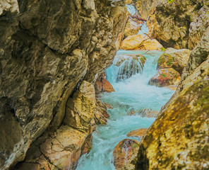 Fototapeta na wymiar Bright turquoise water in a brook in a gorge with cascades
