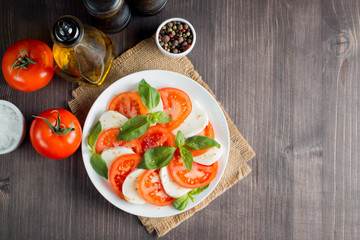 Close-up photo of caprese salad with ripe tomatoes, basil, buffalo mozzarella cheese. Italian and Mediterranean food concept. Fresh and healthy organic meal. Starter and antipasti.