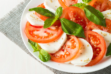 Close-up photo of caprese salad with ripe tomatoes, basil, buffalo mozzarella cheese. Italian and Mediterranean food concept. Fresh and healthy organic meal. Starter and antipasti.