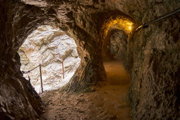 Obraz premium Poorly lit tunnel next to the narrow path along a gorge through the mountains of the Alps in the south of Germany at the border to Austria.