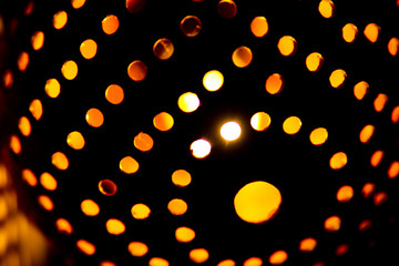 Coconut shell lamp with holes casting spotty yellow orange color round light pattern on the wall