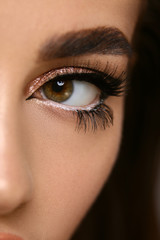 close-up of woman cat eye with golden shadow isolated on black