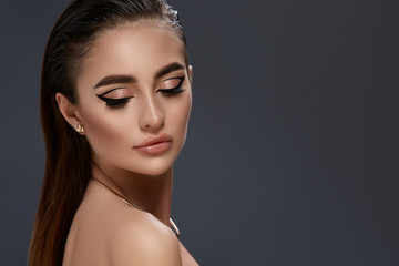 elegant woman with luxury evening make-up and golden jewelry isolated on black