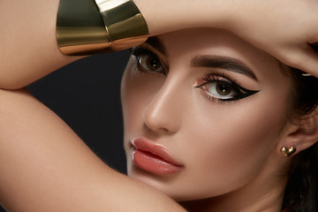 luxury golden and black make-up on brunette face with golden jewelry