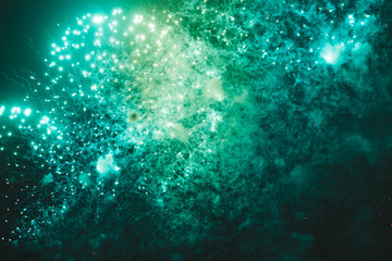 Fototapeta na wymiar Blue and green festive fireworks on a black background. Abstract holiday background. International Fireworks Festival ROSTEC