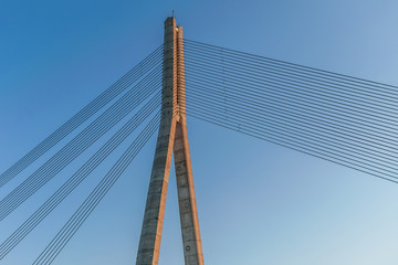 the top of the cable-stayed bridge support against a bright blue sky