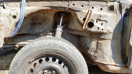 A stand of an old and rusty car closeup. Auto part close-up. A wrecked car at a car service is not subject to restoration and repair
