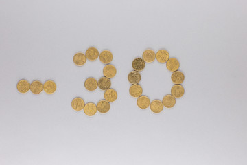 -30 made from coins shot from above, on white background.