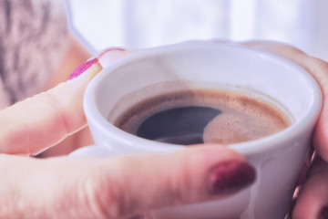 A cup of morning aromatic coffee in the hands with manicure.