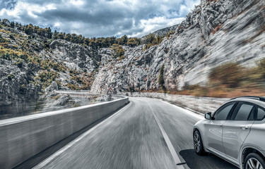 White car on a mountain road. Highway among the mountain scenery. Toned photo.