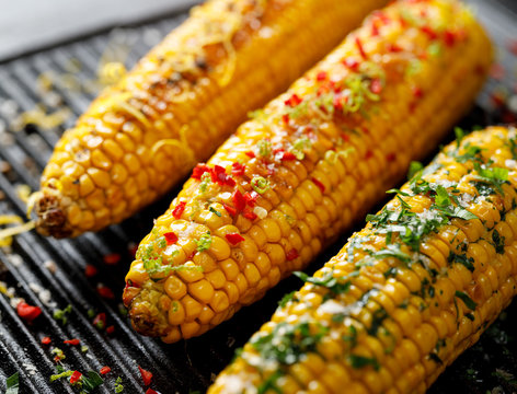 Grilled Corn On The Cob With Butter, Herbs, Salt And Aromatic Spices On The Grill Plate, Close-up