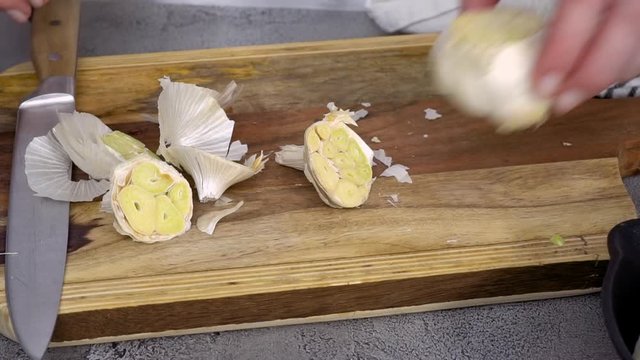 Preparing garlic spread by roasting garlic with fresh spices in cast iron frying pan.