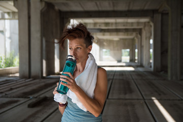Beautiful fitness athlete woman drinking water after work out exercising