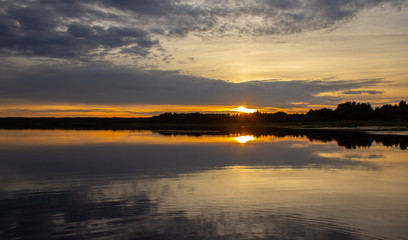 Naklejka na ściany i meble Evening at the lake. Water surface. Beautiful sunset.
