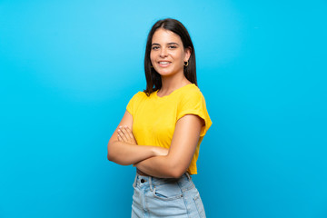 Fototapeta na wymiar Young girl over isolated blue background with arms crossed and looking forward