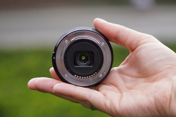 photo lens in hand of man against city on background of green and red brick wall. modern technology and the old town. lense through video photo digital glass hand blurred focus people concept