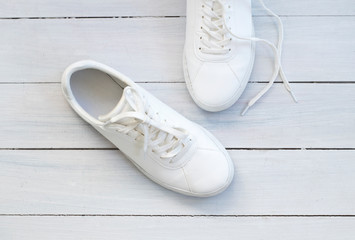 Fashion blog or magazine concept. White female sneakers on wooden background. Flat lay, top view minimal background.