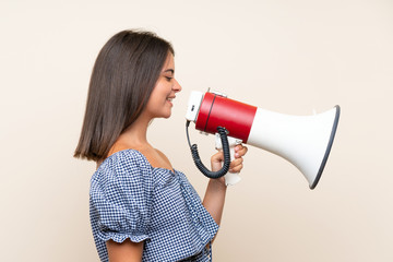 Young girl over isolated background shouting through a megaphone