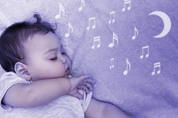 Little child falls asleep in the night light with music: concept of baby sleep