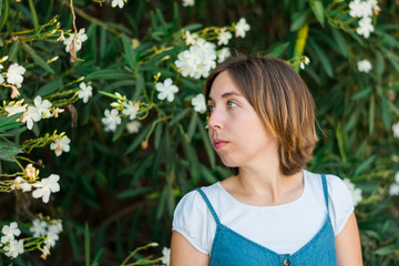 Close up portrait of a young woman with blue eyes with green plants on the background