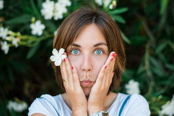 Close up portrait of a young woman with blue eyes with green plants on the background