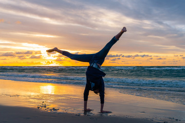 Young girl exercising on a seaside beach at sunset