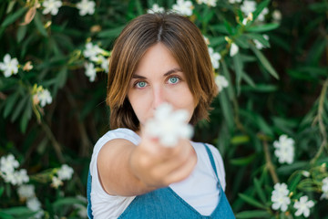 Close up portrait of a young woman with blue eyes with green plants on the background