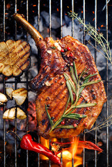 Grilled bone-in pork chop, pork steak, tomahawk in a rosemary-garlic marinade  on a flaming grill plate, close-up, top view. Barbecue, bbq meat - 284903650