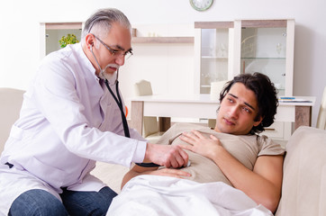 Obraz premium Old male doctor visiting young male patient