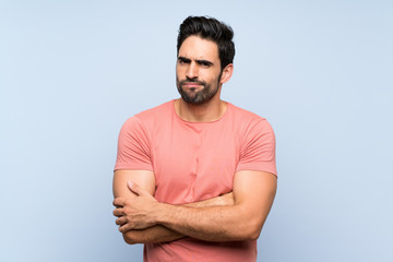 Handsome young man in pink shirt over isolated blue background feeling upset