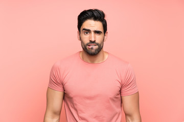 Handsome young man over isolated pink background having doubts and with confuse face expression
