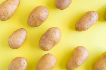 Obraz premium Raw potatoes on a yellow background.