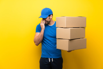 Young delivery man over isolated yellow wall smiling a lot