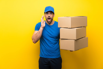 Fototapeta na wymiar Young delivery man over isolated yellow wall with surprise and shocked facial expression