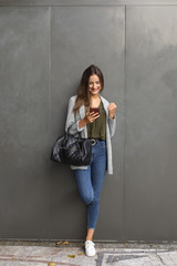 Cheerful young professional woman looking her smartphone and doing success positive gesture outside.Successful casual business woman getting good news on her cell phone.