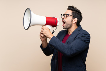 Handsome young man over isolated background shouting through a megaphone