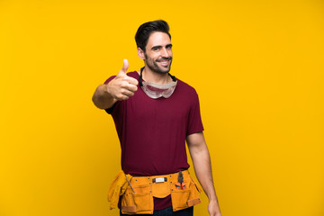 Handsome young craftsman over isolated yellow background with thumbs up because something good has...