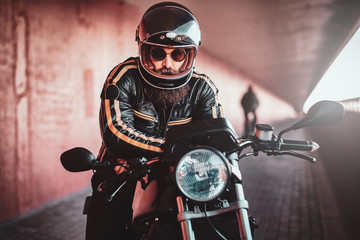 Fototapeta na wymiar Brutal bearded biker in helmet and leather jacket is ready to go.