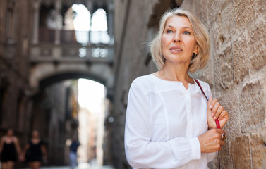 Elegant mature woman is posing in time walking on the street of old city