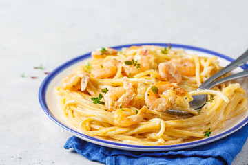 Shrimp pasta with cream and herbs in white plate, copy space.