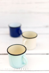 Enameled mugs in retro style on an old wooden background.