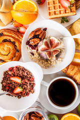 Breakfast table with oatmeal, waffles, croissants and fruits.