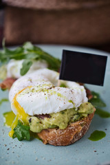 Close-up poached egg with yolk on toast with avocado and salad
