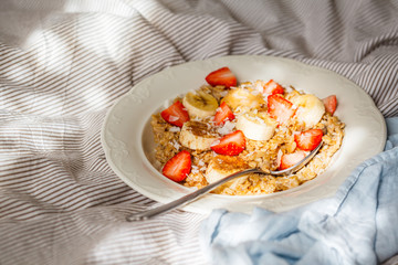 Oatmeal with banana, strawberries and peanut butter in white plate in bed backgrond.