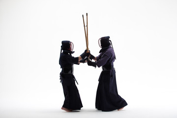 two Kendo martial arts fighters combat fighting in silhouette isolated on white bacground